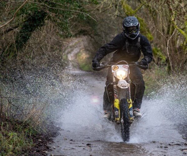 Ollie Moto riding his Husqvarna FE350 through a river in the Cotswolds.
